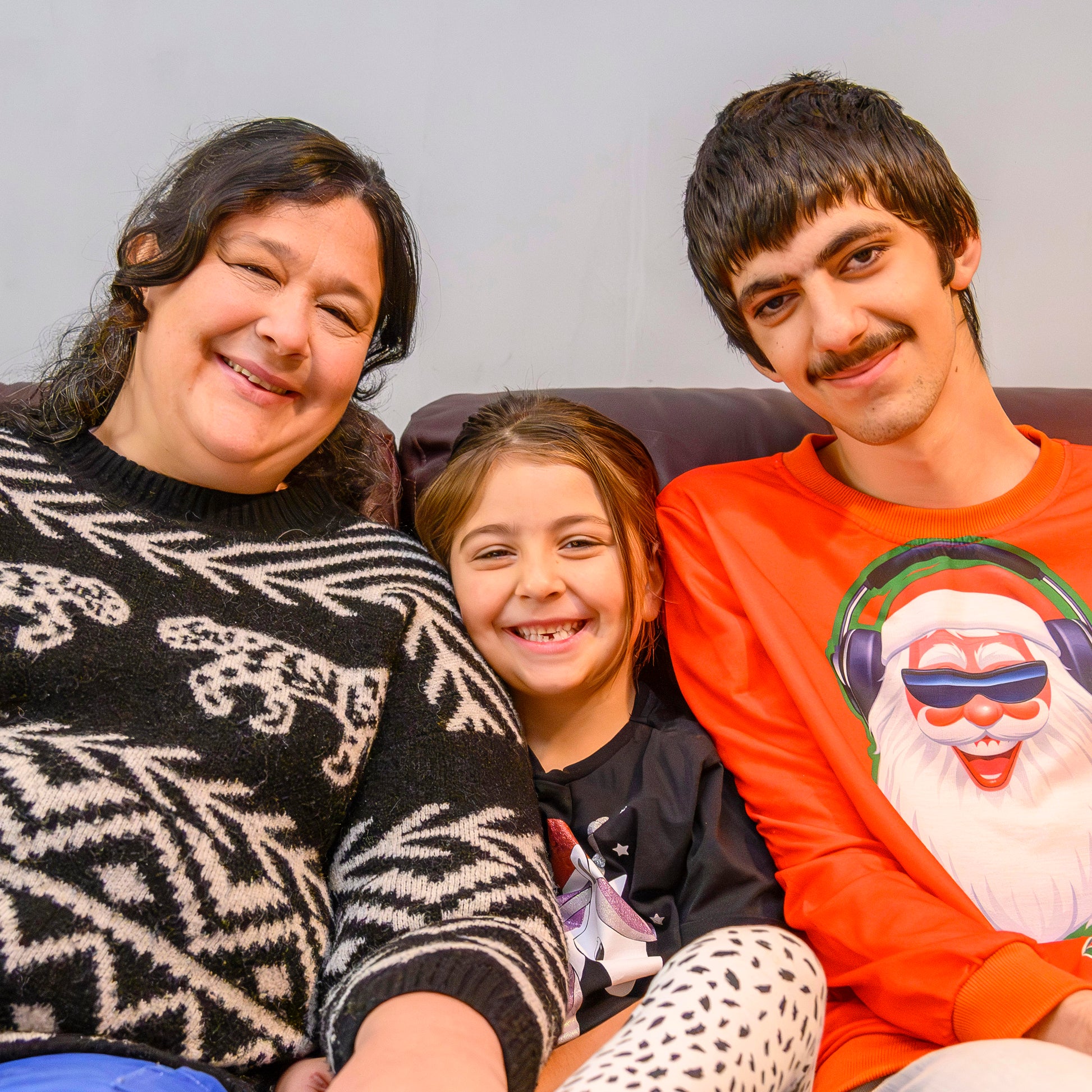 Family of three smiling together on a sofa